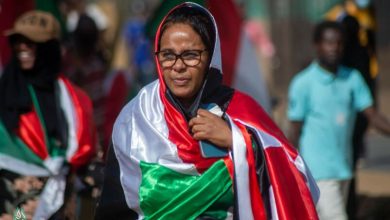 سيدة تلتحف بعلم السودان خلال مشاركتها في إحدى الاحتجاجات