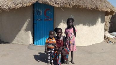 لاجئة جنوب سودانية مع أطفالها أمام مسكنهم المستداام في ولاية النيل الأبيض بالسودان